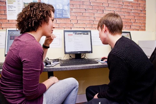 A couple of people looking at a computer
Description automatically generated